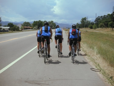 Kelly, Mark, Jenn, Dave S., and Catherine bike while the Rocky Mountains loom threateningly in the distance. The Rocky Mountains do that very well.